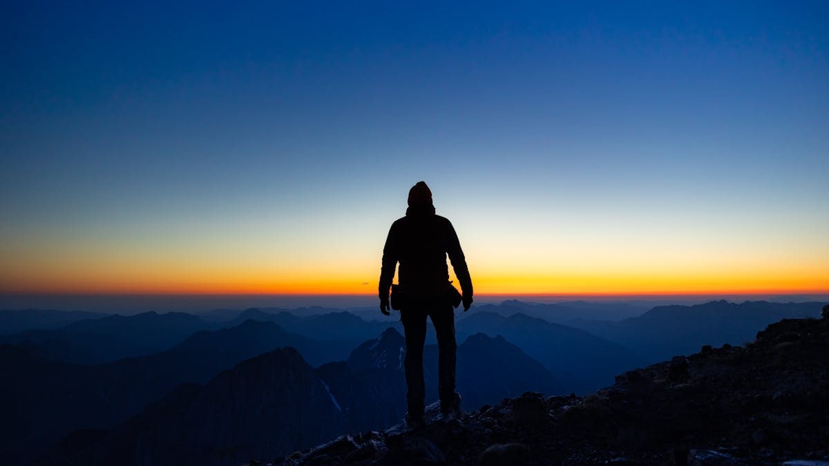 Silhouette of a hiker observing a breathtaking sunrise over the Austrian Alps.